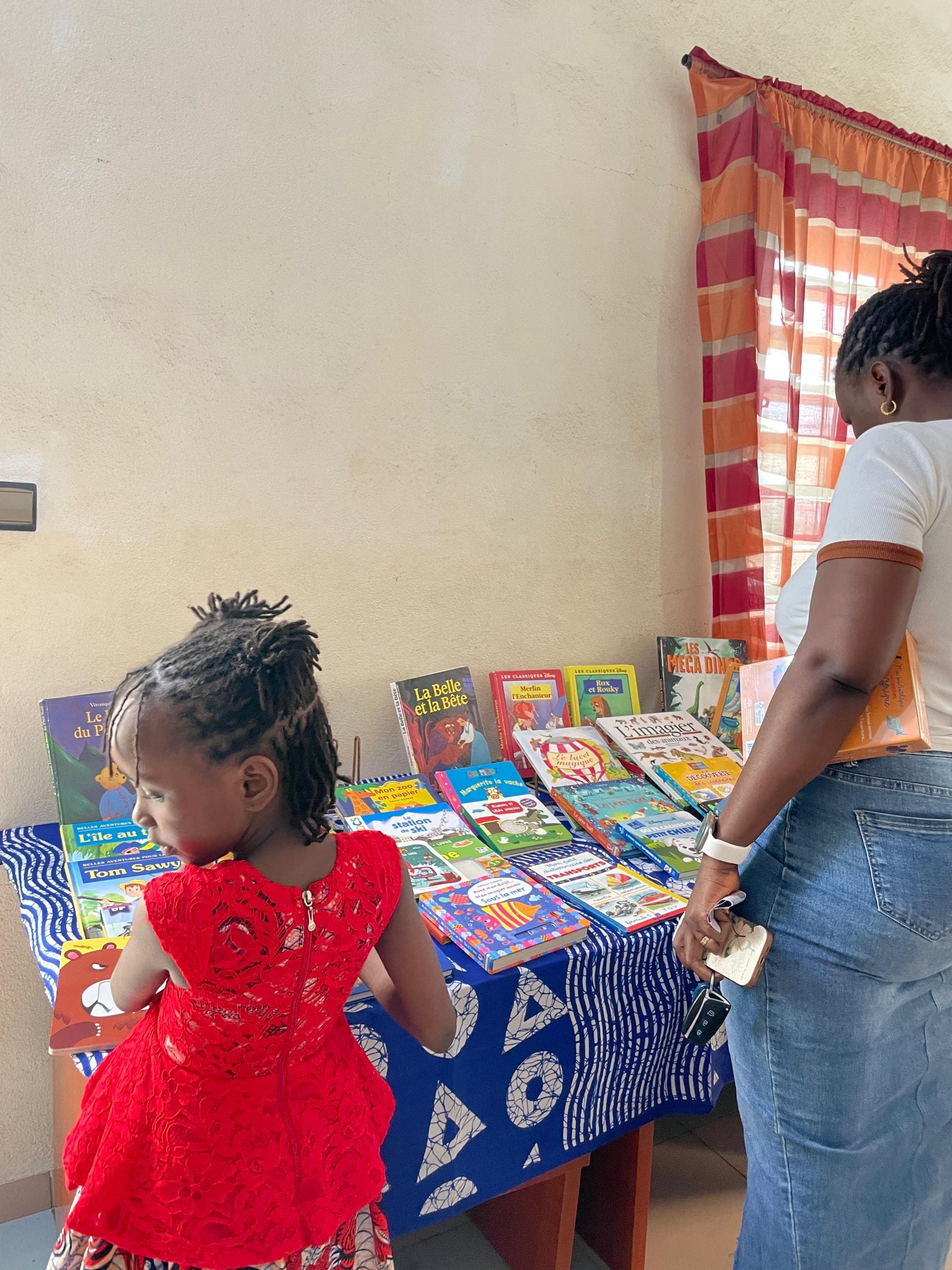 Une petite fille et sa maman devant une table de livres pour enfants